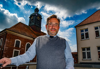 Ein Mann steht lächelnd vor einer Kirche.  - Copyright: Bastian Modrow