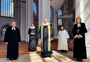 Fünf Pastor:innen, im Hintergrund der Innenraum der Lübecker Petrikirche. - Copyright: Bastian Modrow