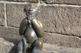 Eine metallene Teufelsfigur vor der Kirche