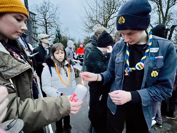 Junge Menschen entzünden eine Kerze