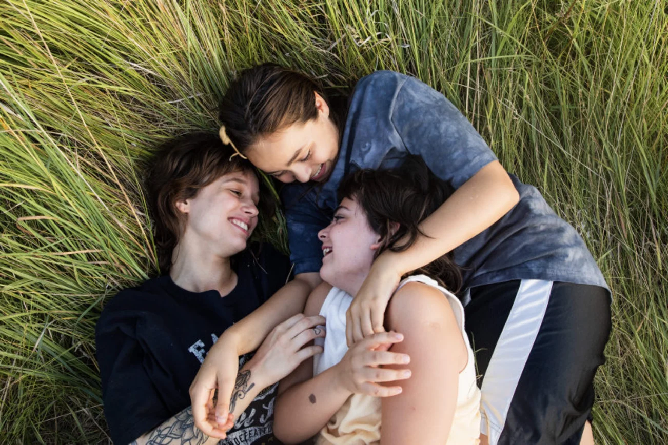 Drei Kinder liegen auf einer Wiese