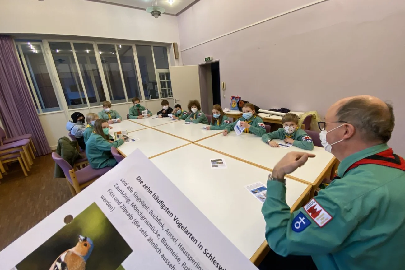 Eine Gruppe Pfadfinder sitzt in einem Raum und lernt. 