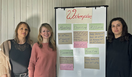 Drei Frauen stehen an einem Flipchart.