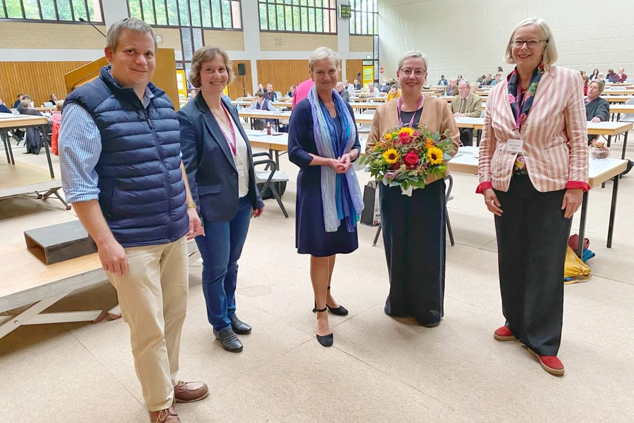 Mehrere Personen stehen lächelnd in einer Sporthalle. 