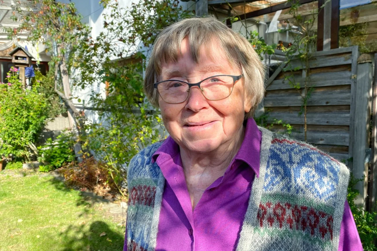 Eine Frau steht in einem herbstlichen Garten 