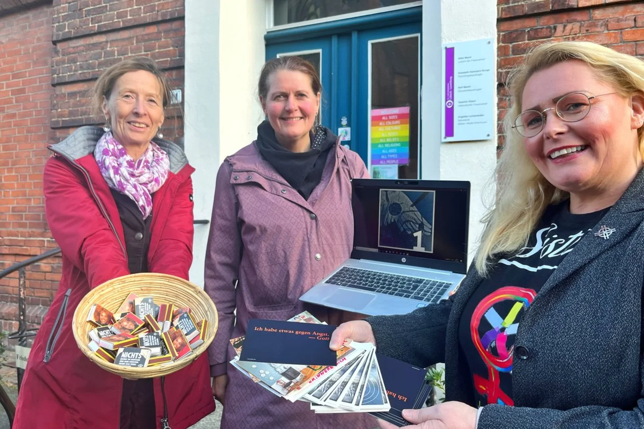 Drei Frauen stehen lächelnd vor einem Haus.