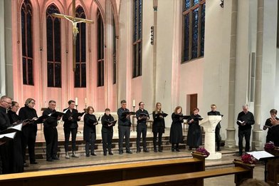 Der Kammerchor St. Johann singt im Altarraum einer Kirche - Copyright: Künstler