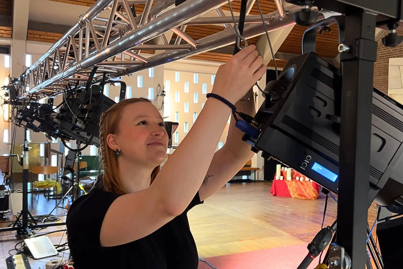 Eine junge Frau arbeitet an einem großen Scheinwerfer.