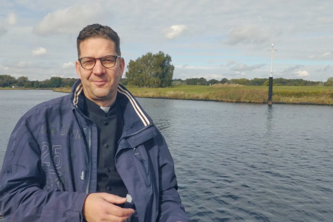 Ein Mann steht vor einer Landschaft und einem Fluss. 