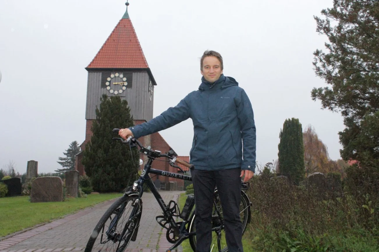 Mann mit Fahrrad vor Kirche