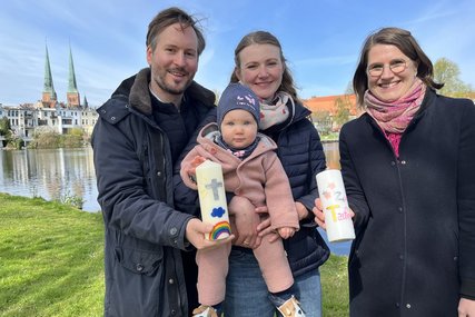 Eine Familie und eine Pastorin stehen vor einem Gewässer - Copyright: Bastian Modrow