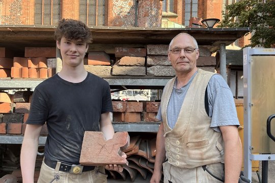 Zwei Männer stehen vor einem Regal mit Ziegelsteinen