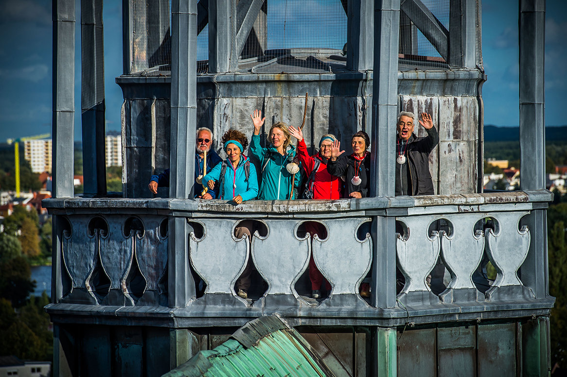 Eine kleine Gruppe steht auf einem Turm und winkt in die Kamera