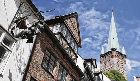 Hinter mehreren Häusern ragt der Turm von St. Petri in den Himmel