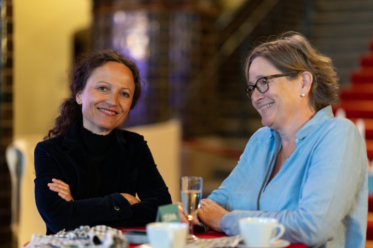 Zwei lächelnde Frauen sitzen an einem Tisch