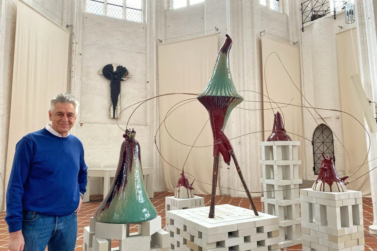 Ein Mann steht nachdenklich in einer Kirche vor einer Keramikskulptur.