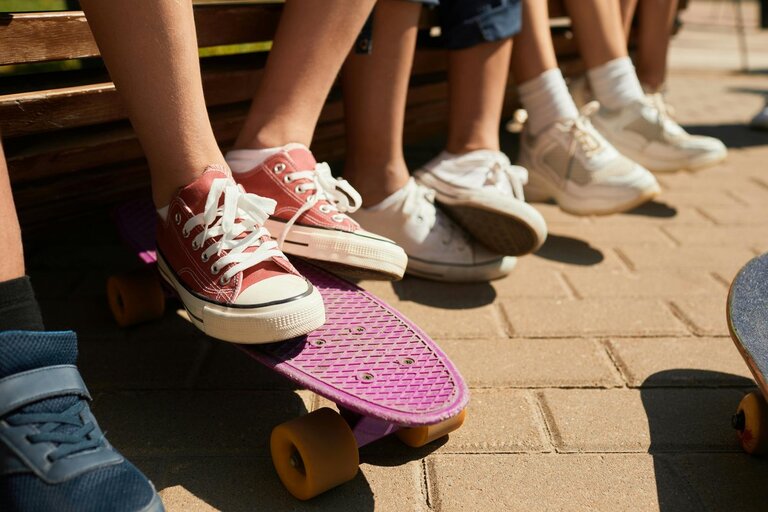 Mehre Füße in Sneakers, davon ein paar auf einem Skateboard