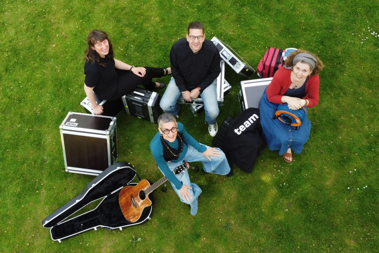 Menschen sitzen mit Kisten auf einem Rasen