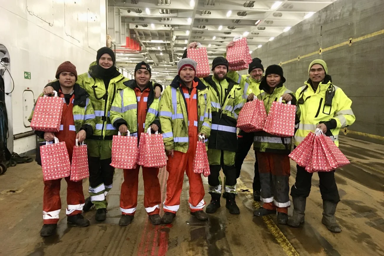 Menschen mit Weihnachtstüten auf einem Schiff