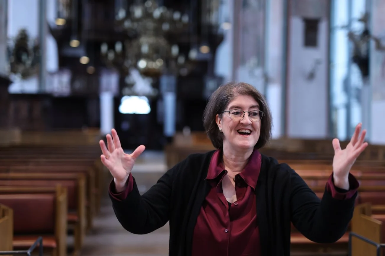 Jakobikantorin Ulrike Gast ist in der St.-Jakobi-Kirche zu Lübeck zu sehen, wie sie dirigiert und dabei lächelt.