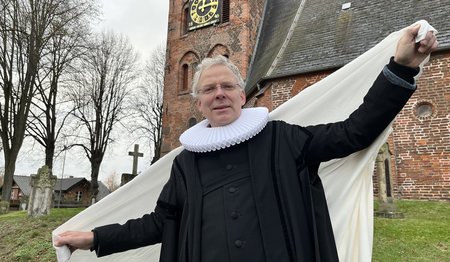 Ein Pastor steht mit einer Decke vor einer Kirche