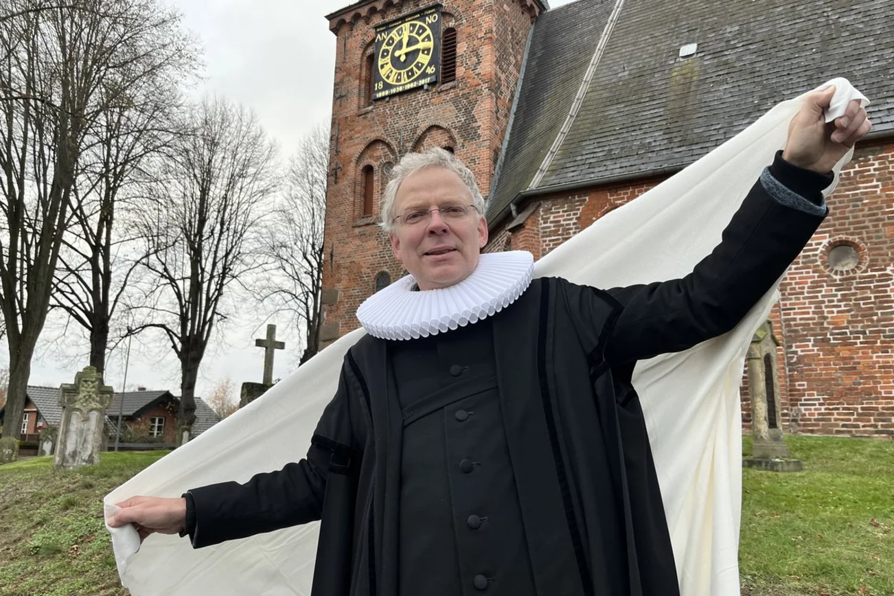 Ein Pastor steht mit einer Decke vor einer Kirche