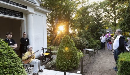 Ein Mann spielt vor einem Mausoleum auf einer Mandola