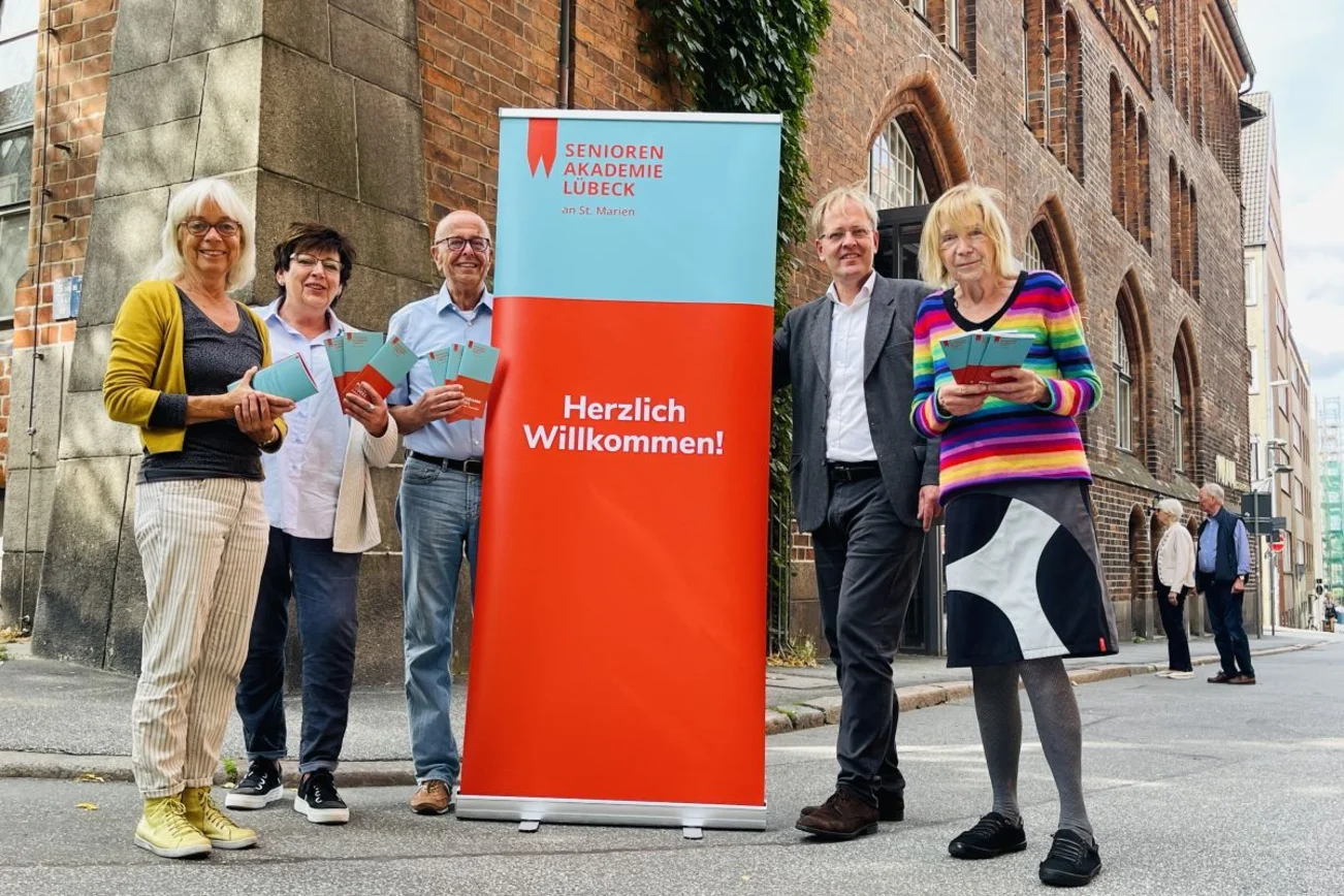 Fünf Personen vor einem Plakat-Aufsteller.