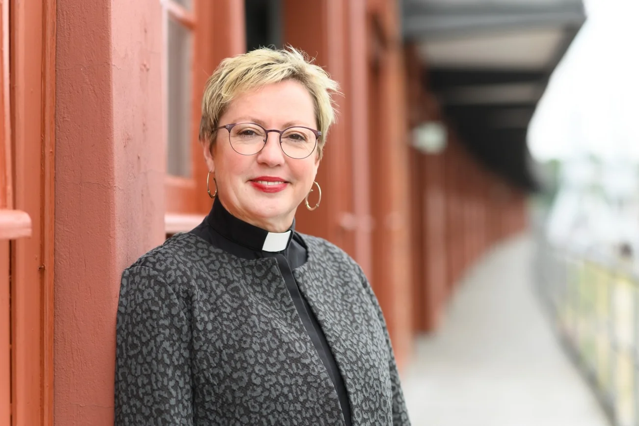 Eine Frau mit kurzen Haaren, Brille und Kollarhemd schaut in die Kamera.
