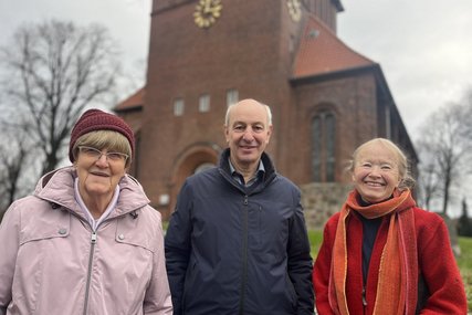 Zwei Frauen und ein Mann stehen im Winter vor einer Kirche. - Copyright: Annkathrin Bornholdt