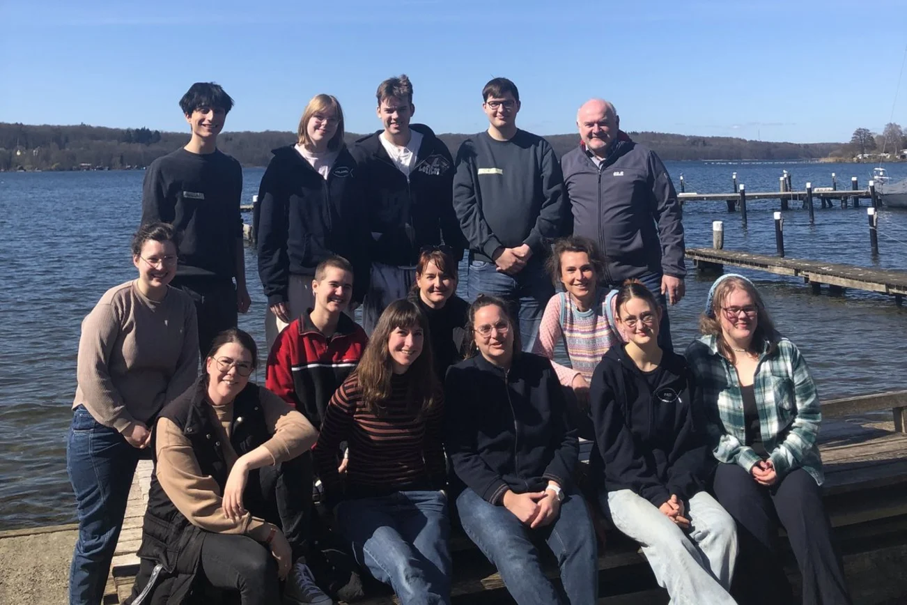Gruppenfoto vor einem See mit blauem Himmel
