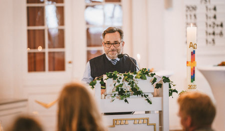 Ein Mann steht am Podium in einer Kirche.