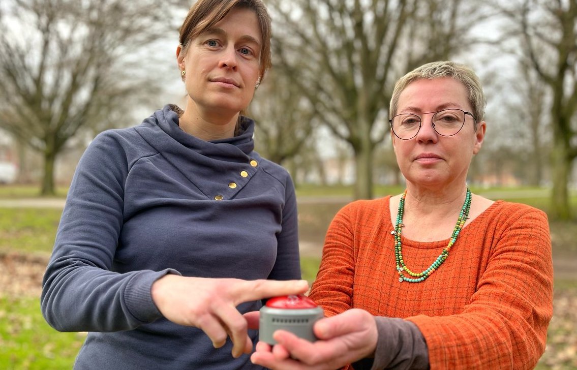 Sei Frauen stehen mit einem Alarmbutton in einem Park