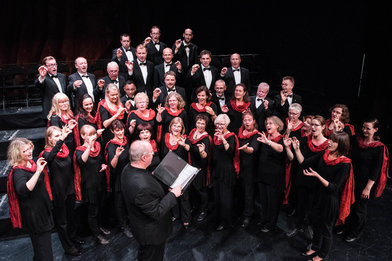 Der Kammerchor der Singakademie Cottbus in schwarzer Konzertkleidung, die Damen zusätzlich mit roten Schals - Copyright: Martin Kross