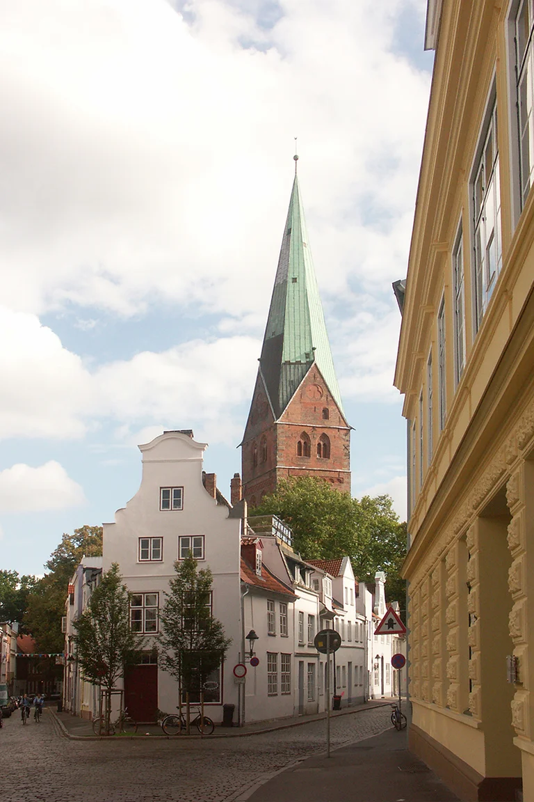 Der Turm der St.-Aegidien-Kirche ragt über die Lübecker Dächer - Im Vordergrund gabeln sich zwei Straßen