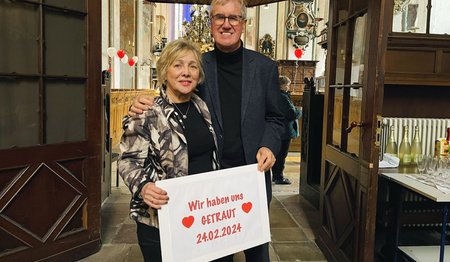 Ein Paar steht in einer Kirche und hält ein Schild in der Hand.