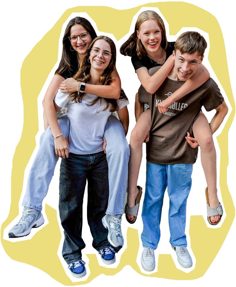 4 Jugendliche, zwei Jugendliche haben einen anderen Jugendlichen huckepack / Hintergrund ist senffarben