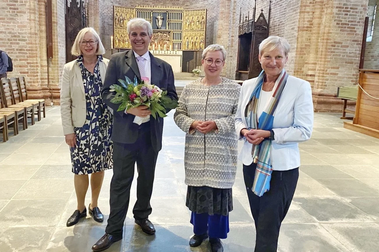 Vier Personen stehen freudig in einer Kirche