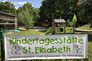 Banner am Zaun vor dem Bespielplatz der KITA mit der Aufschrift Kindertagesstätte St. Elisabeth 