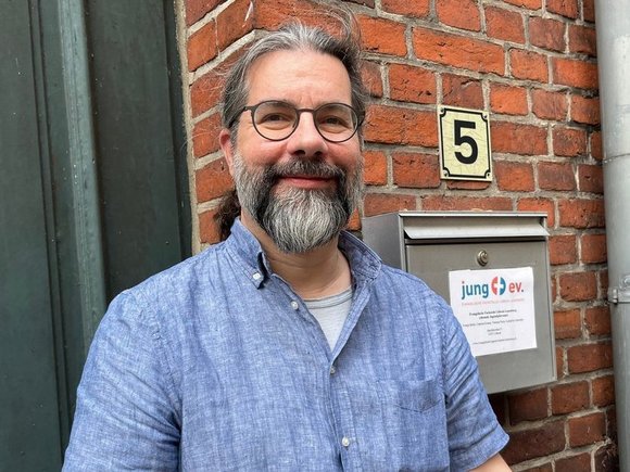 Mann schaut lächelnd in die Kamera