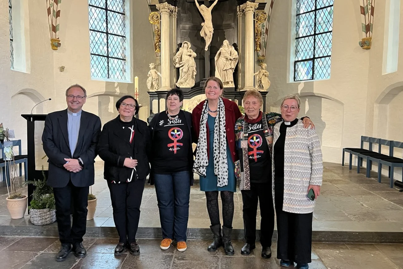 Sechs Personen stehen in einer Kirche