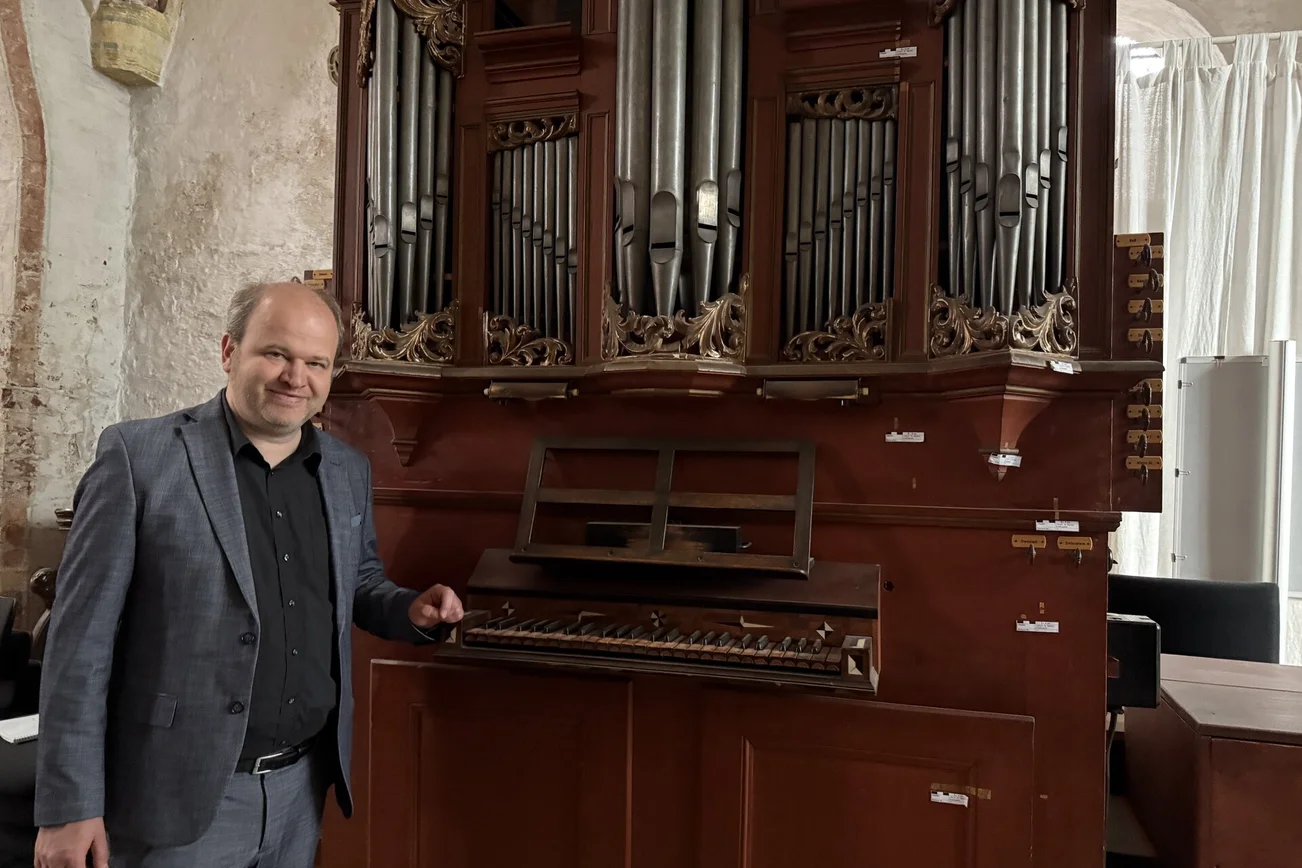 Ein Mann steht an einer Orgel.