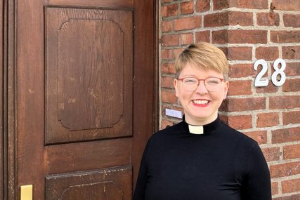 Eine Frau mit kurzen Haaren steht vor einer Eingangstür aus Holz - Copyright: Christina Lubowski