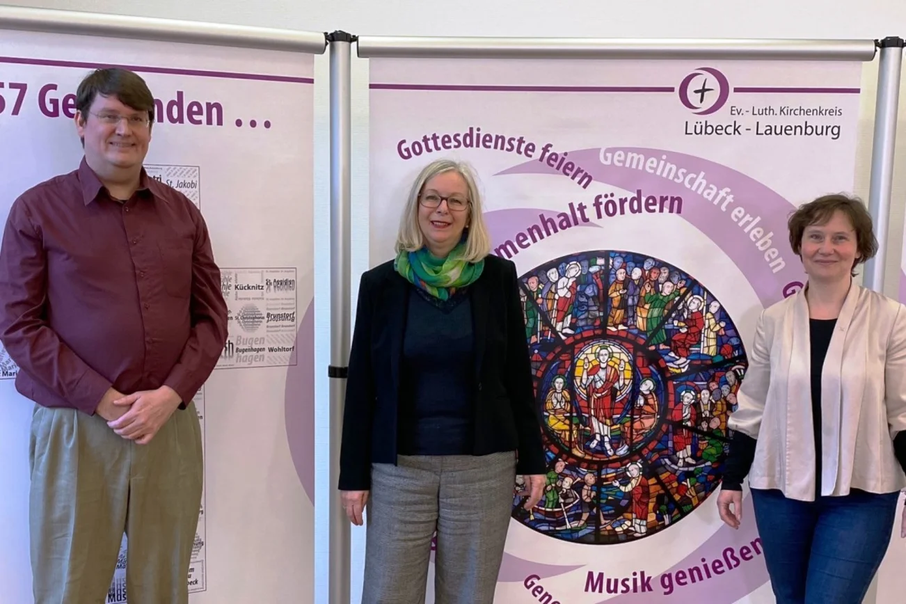 Ein Mann, zwei Frauen blicken freundlich in die Kamera.