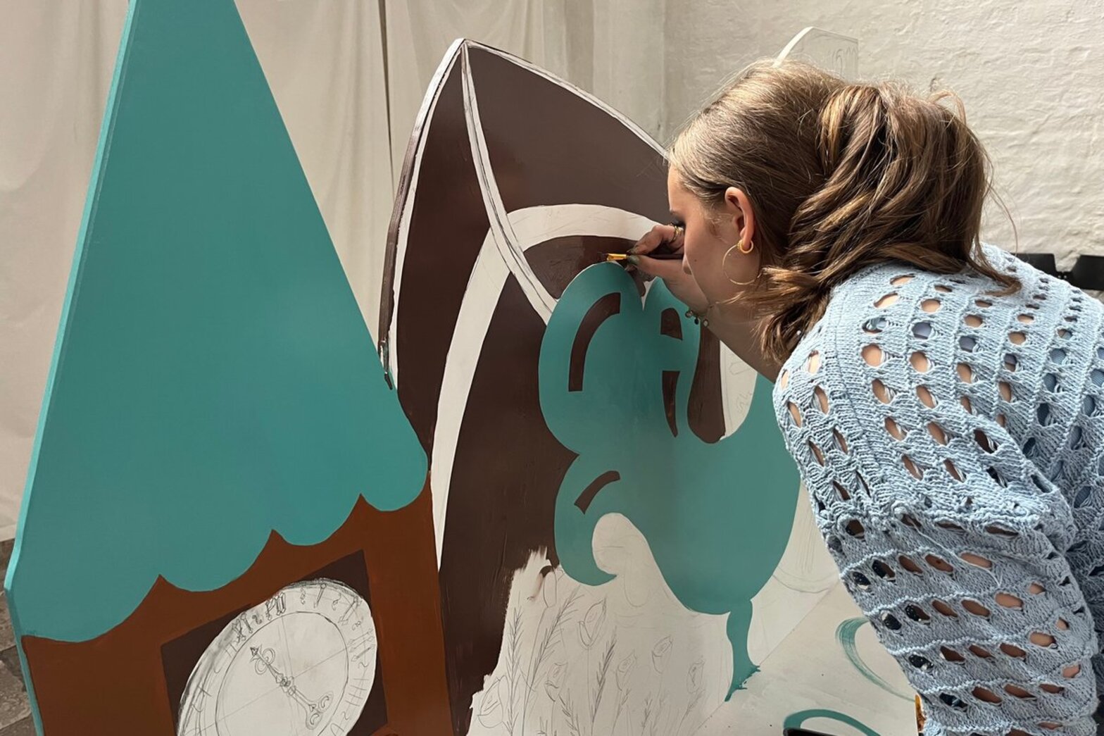 Die Schülerin malt mit einem Pinsel auf die Kirchenbank.