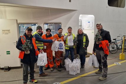 Seeleute stehen an Deck eines Schiffes mit Geschenktüten in der Hand. - Copyright: Deutsche Seemannsmission Lübeck