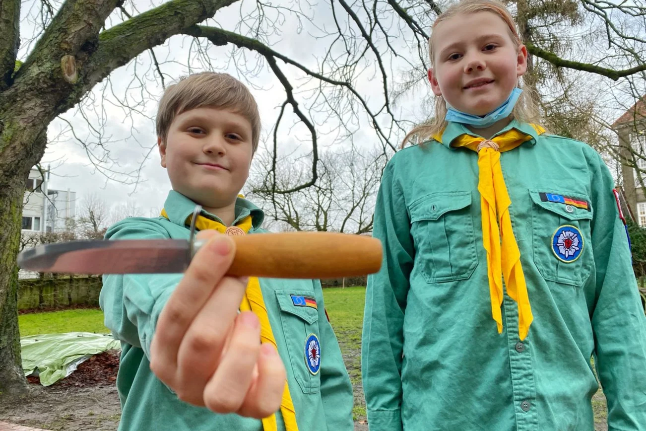 Zwei junge Pfadfinder zeigen ihr Pfadfinder-Messer. 