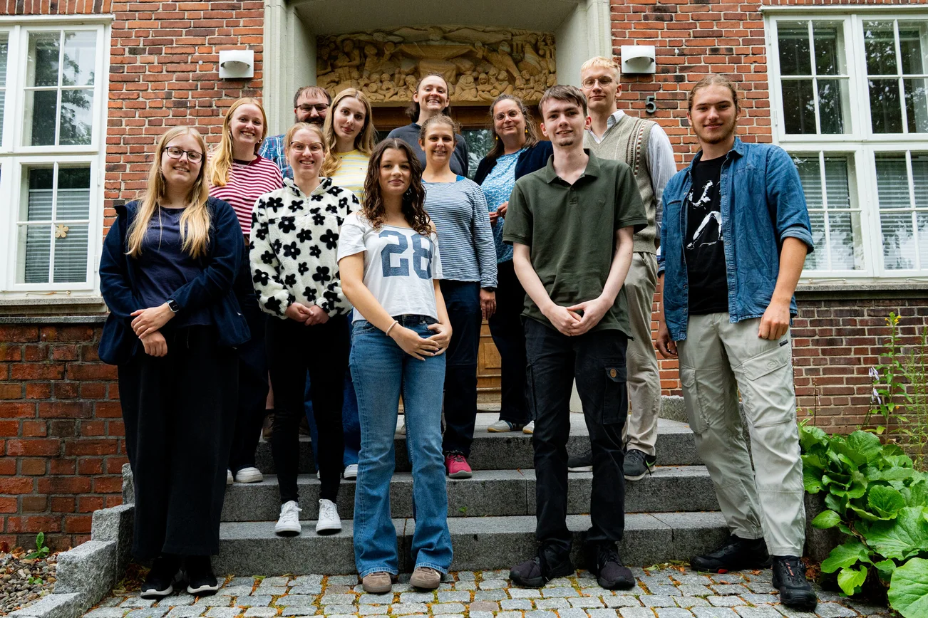 Eine Gruppe junger Menschen steht auf einer Treppe für ein Gruppenfoto zusammen.