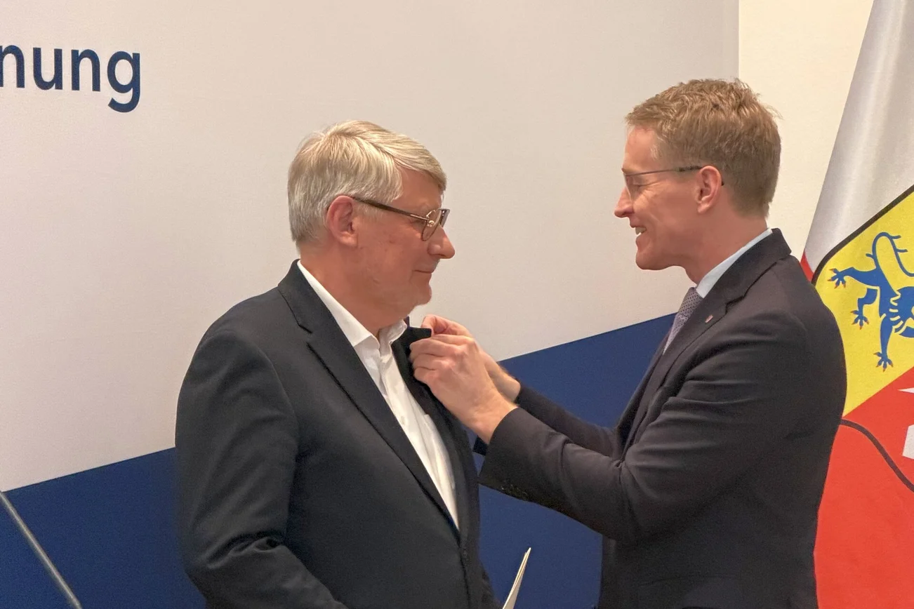 Ein junger Mann steckt einem älteren Mann eine Nadel ans Revers.