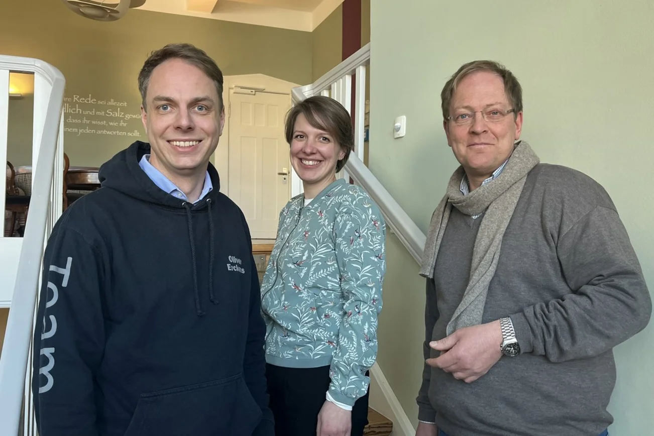Zwei Männer und eine Frau stehen auf einer Treppe.